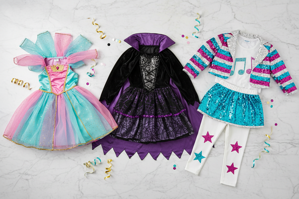 top view flat lay of three girls party costumes for kids aged 6-10 years. One princess or fairy, one fun witch or vampire and one popstar. Color palette mainly : pink, turquoise, white, gold and black accents. Light marble background with subtle ribbons and confetti. Cute, magical and playful look. No toddlers, no baby outfits, no onesies, no accessories, no ballet tutus, no baby look. Clothing only, no models.