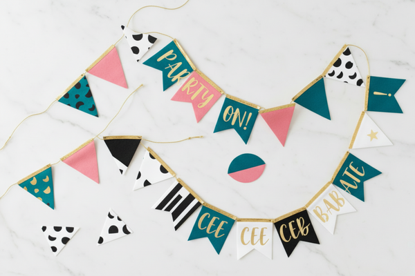 Playful yet elegant  flat lay composition of buntings and banners. Color palette: turquoise, black, white, medium-saturated pink, gold accents. Soft white marble texture background, high-end product photography, bright and joyful tones, subtle movement and flow, playful arrangement, confetti details. No lace.